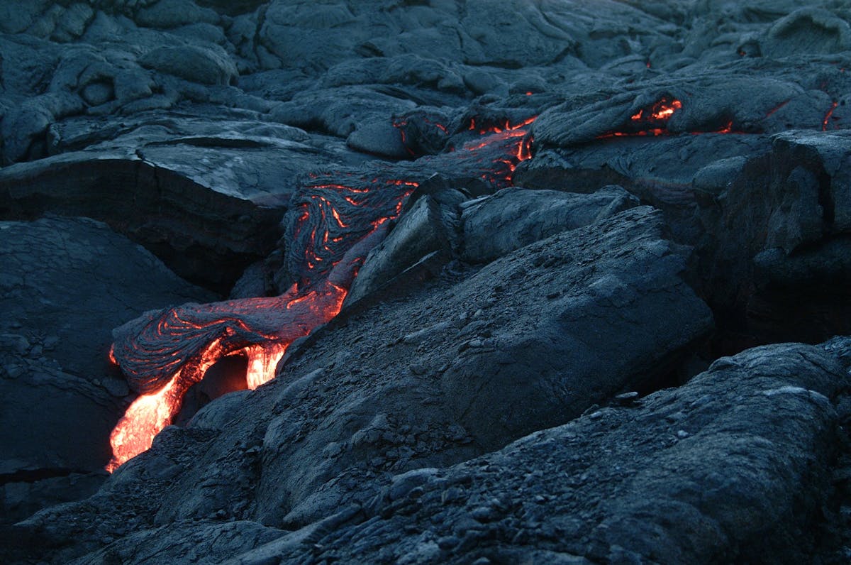 Glowing molten lava flowing through dark volcanic rock - the urgent, burning quality of activation